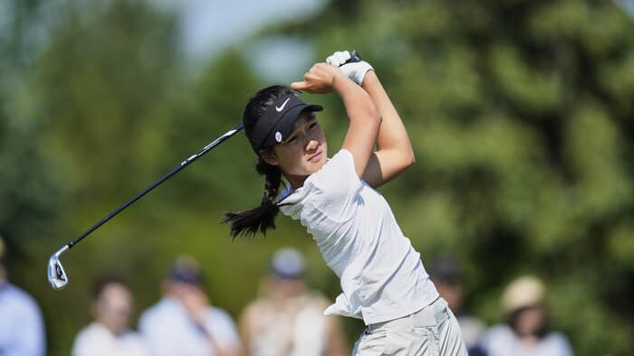 Golfer swinging on a course.